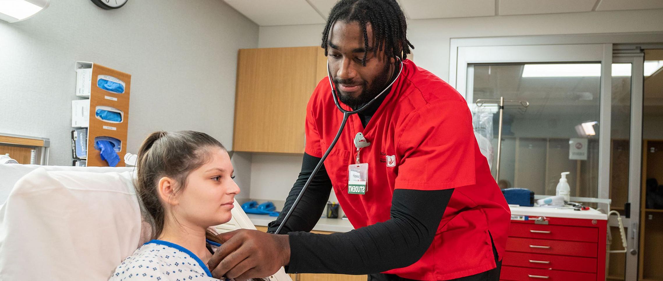 全球十大赌钱排行app in Wisconsin offers a nursing major. Pictured here is a nursing student listening to a person's heart rate in the simula...